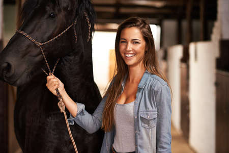 Hey girl, why. Portrait of a young woman in a stable with her horse.