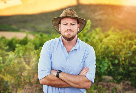 Im my own boss besides for Mother Nature. Cropped shot of a middle-aged farmer posing on a vineyard.の写真素材