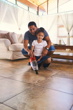 Shes learning a lot from dad. Shot of a father and daughter vacuuming the floor.の写真素材