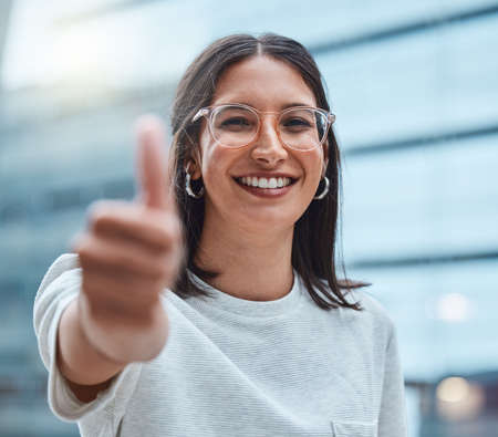You pulled it off and Im super proud of you. Shot of a young businesswoman showing thumbs up against an urban background.の写真素材