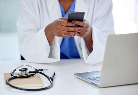 Technology makes my work so much easier. Shot of an unrecognizable doctor using a phone and laptop at work.の写真素材