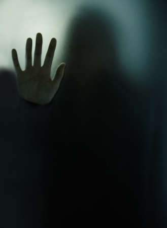 Isolated and doomed. Cropped shot of woman behind a glass wall during quarantine.