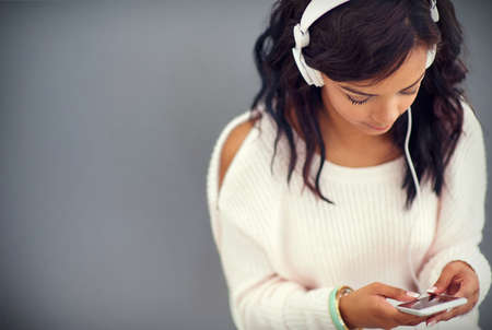 She never misses an episode of her favorite podcast. Studio shot of a young woman listening to music...