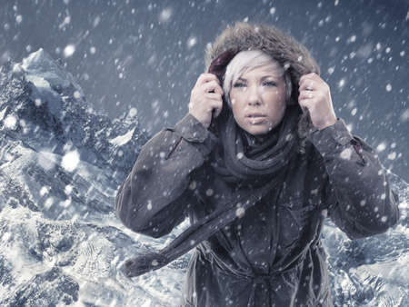 Braving the conditions to reach the top. Cropped shot of an attractive young woman hiking in the midst of a snow storm.の写真素材