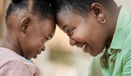 A mothers love. Cropped shot of an attractive young woman and her daughter standing face to face with their heads touching in the living room at home.の写真素材