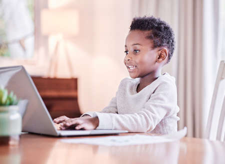 There is no end to education. Shot of a young boy doing his homework on a laptop at home.の写真素材