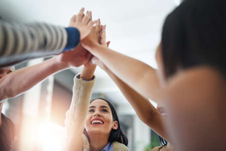 Accomplishing great things together. Shot of a group of happy friends high fiving each other in a cafe.の写真素材