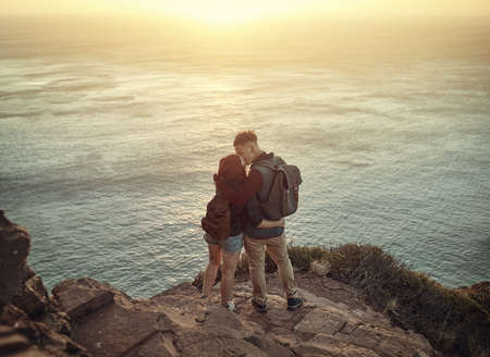 Elevated love. High angle shot of an affectionate young couple kissing on a mountaintop.