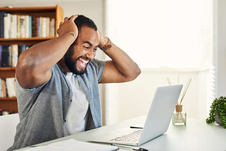 I just scored big. Shot of a handsome businessman looking excited while working from home.