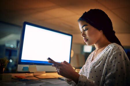 The connected worker is a productive worker. Shot of a young businesswoman using a digital tablet during a late night at work.の写真素材