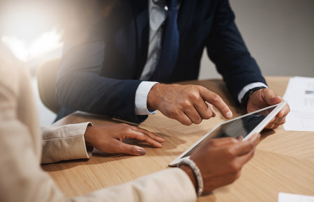 Technology is there to help improve your plans. Closeup shot of two unrecognizable businesspeople using a digital tablet in an office.の写真素材
