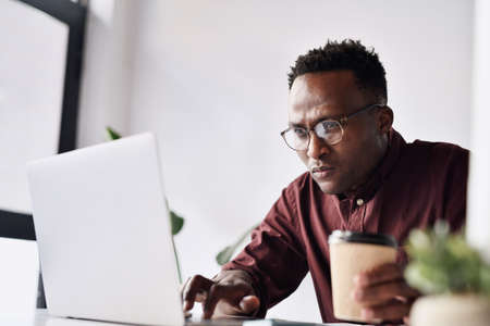 Surviving on coffee to get me through my work. Cropped shot of a handsome young businessman sitting...