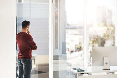 Looking out the window to find inspiration. Shot of a businessman in the office.の写真素材