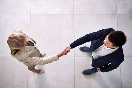 Welcome to the company. High angle shot of two professional businesspeople shaking hands in the office.の写真素材