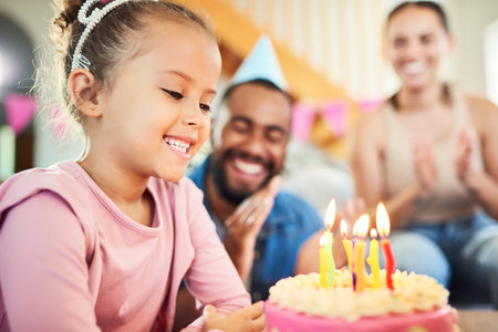 All your wishes can come true. Shot of a little girl celebrating a birthday with her parents at home.の写真素材