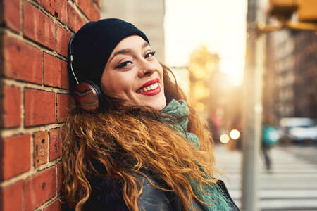 Music is the best therapy. Cropped shot of a young woman listening to music while leaning against a...
