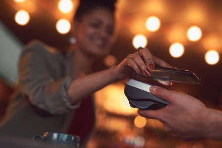 For a quick, easy and paperless transaction. Closeup shot of a woman paying using NFC technology in...