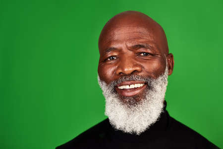 Its important to never stop smiling. Studio shot of a senior man posing against a green background.の写真素材
