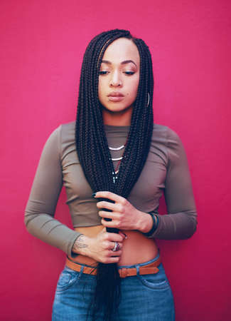 Be true to who you are. Shot of an attractive young woman with braids posing against a pink...