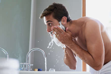 Start your day with a splash. Cropped shot of a handsome young man in his bathroom.の写真素材
