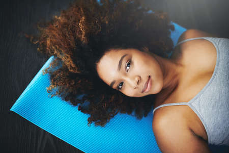 She feels most calm after a yoga session. High angle shot of a young woman practising yoga.の写真素材
