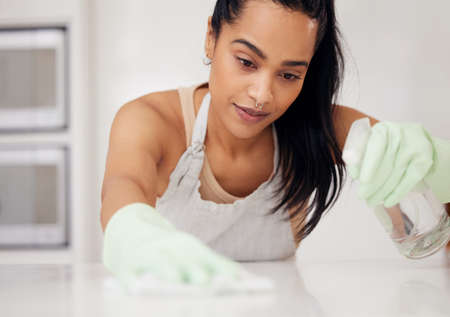 They need to be shiny. Shot of a young woman cleaning a counter at home.の写真素材