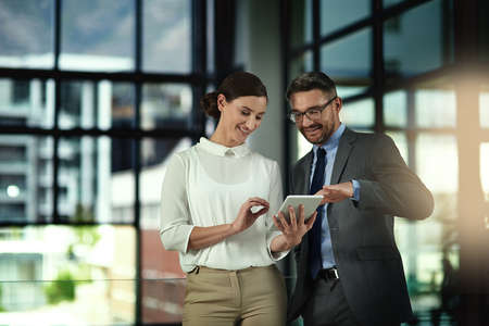 Impressive. Shot of two businesspeople looking over a tablet in the office.