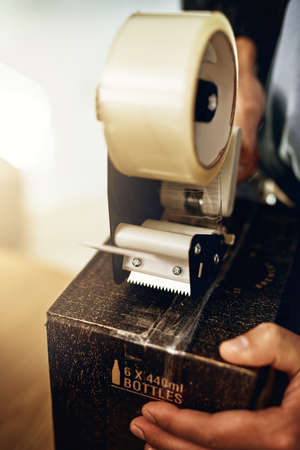 All sealed and ready to ship. Closeup shot of a delivery man sealing a box with tape.の写真素材