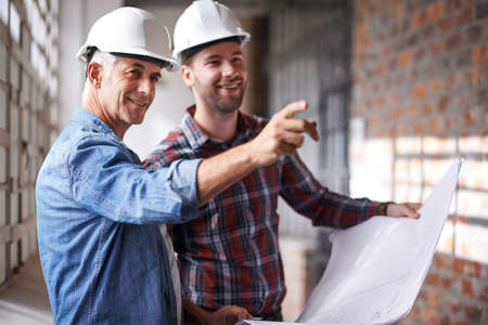 Lets start over there. Shot of two male architects wearing hardhats inspecting a building.の写真素材