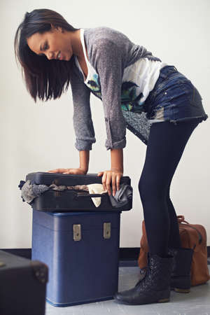 I dont travel light.... A woman trying to close an over-full suitcase.の写真素材