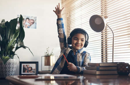 Learning never stops, not even in lockdown. Shot of an adorable little boy using headphones and...