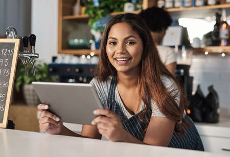 Technology is an integral part of how restaurants operate. Portrait of a young woman using a digital...