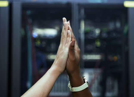 Oh yes. Cropped shot of two unrecognizable female programmers high fiving in a server room.の写真素材