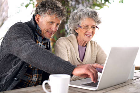 That looks interesting. Shot of a senior couple using a laptop at an outside table.の写真素材