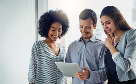 The collaborative team is a productive team. Shot of a group of young businesspeople using a digital...