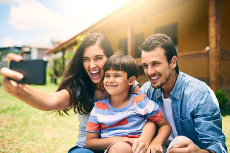 These ones are for the photo album. Cropped shot of a happy young family of three taking selfies...