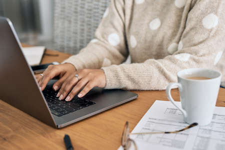 Youll always find a more convenient way online. Cropped shot of a woman using her laptop while working from home.の写真素材