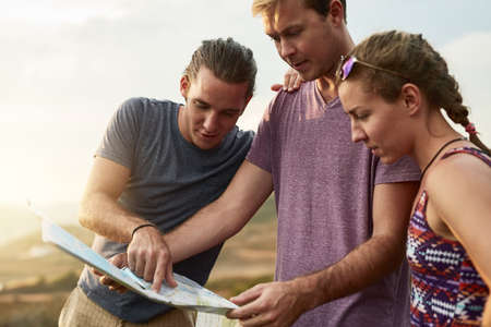 Where to wander next. Shot of three young hikers consulting a map while exploring a new trail.