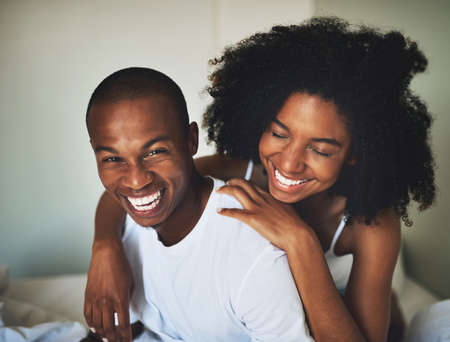 Start everyday the fun way. Portrait of a happy young couple having fun together in bed at home.の写真素材