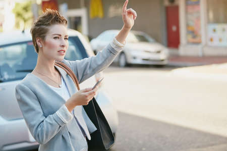 She knows her way around the city. Cropped shot of a young businesswoman gesturing to get a cab in...
