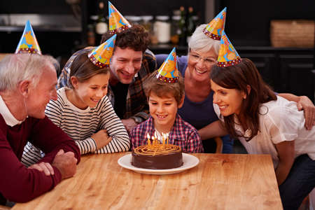 Make a wish before you blow them out. Shot of a happy young boy celebrating his birthday with his family.の写真素材