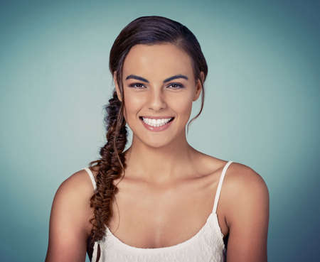 Take every chance, try different hairdos. Studio shot of a beautiful young woman posing against a green background.の写真素材