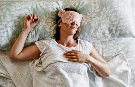 Every girl needs her beauty sleep. Shot of an attractive young woman sleeping with a sleep mask on in her bed at home.の写真素材