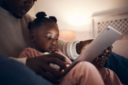Daddy read me a story please. Shot of a father reading his daughter bedtime stories.の写真素材