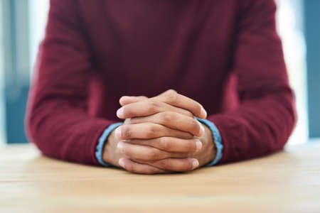 Patience breeds success. Shot of an unidentifiable businessman sitting with his hands folded in the office.の写真素材