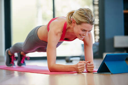 Following some fitness tutorials online. Shot of a sporty young woman working out at home.