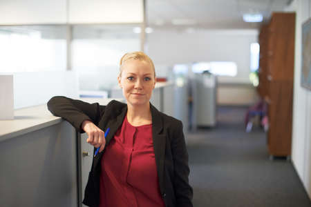 Feeling relaxed in the workplace. Portrait of an attractive businesswoman standing in the office.の写真素材