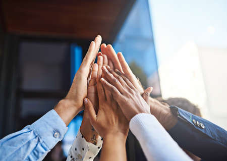 Celebrating another job well done. Cropped shot of a group of unrecognizable colleagues giving each other a high five.の写真素材