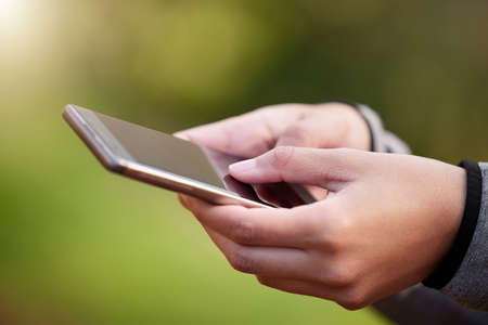 Im hooked on this app. Cropped shot of an unrecognizable woman using her cellphone while standing...