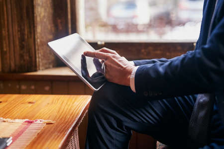 Taking a break from the office. Cropped shot of a well-dressed mature man using a digital tablet in a cafe after work.の写真素材